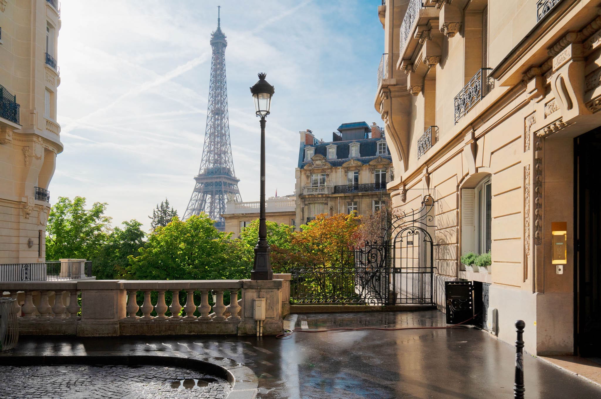 View of the Eiffel Tower framed by elegant Parisian architecture and a quiet courtyard in the heart of Paris, France.