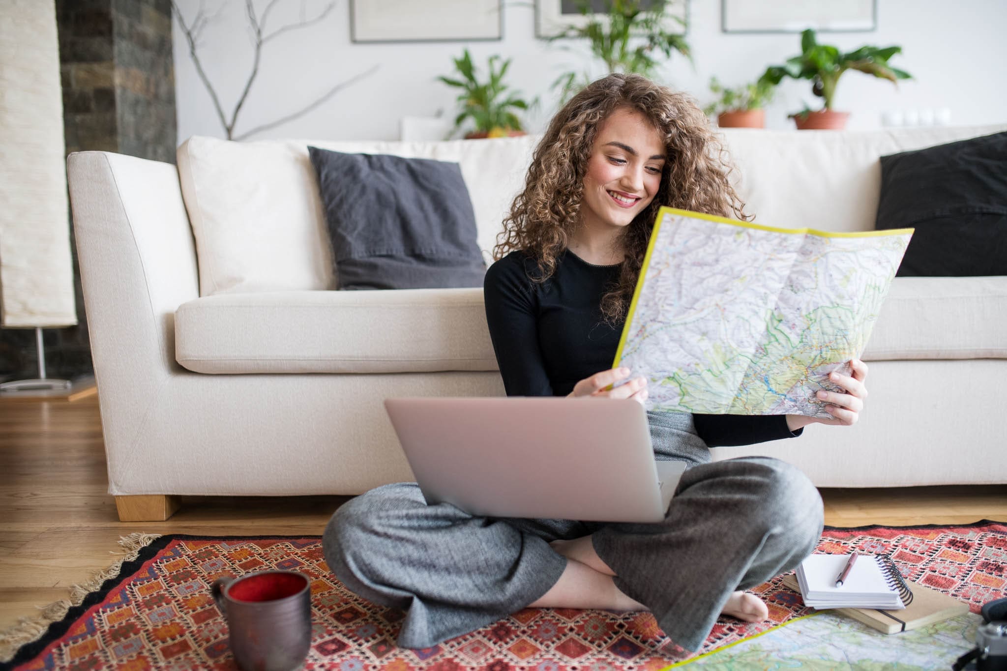 Woman planning a European vacation with a map, laptop, and travel itinerary.