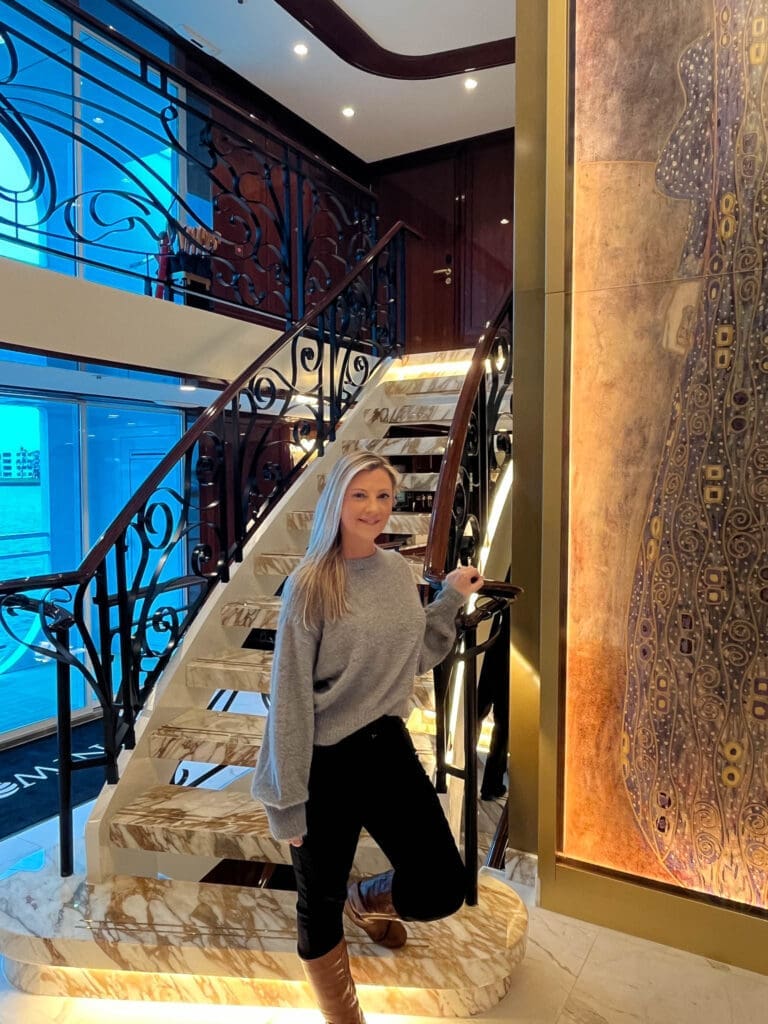 Stacy, founder of Epic Sands Travel, exploring the elegant staircase aboard a luxury European river cruise ship.